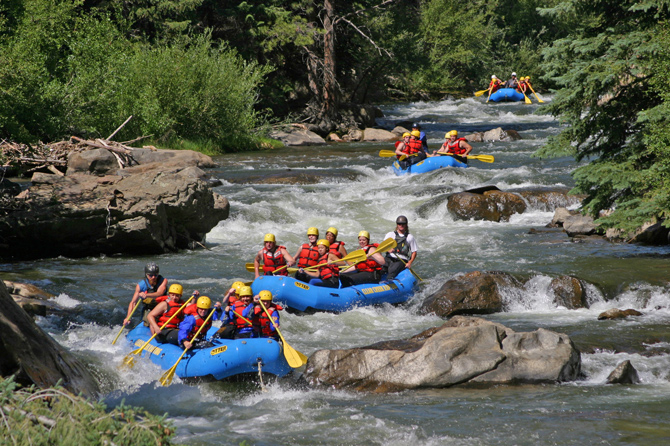 Rafts from Clear Creek Rafting Company float down the Arkansas River near Royal Gorge, Colorado.