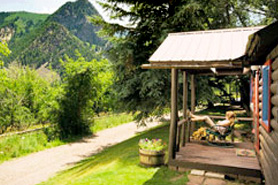 Woman relaxing on cabin porch at Avalanche Ranch Cabins and Hot Springs in Crystal River Valley near Glenwood Springs, Aspen, and Snowmass Village, Colorado