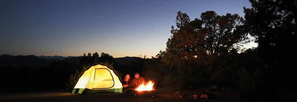 Two campers snuggling by campfire and tent at Echo Canyon Campground in the Royal Gorge Area