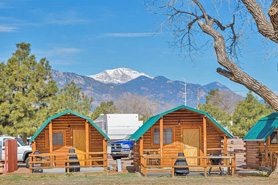 Cabins in front of mountains with Colorado Springs KOA in Colorado Springs, Colorado. View Pikes Peak with a cabin for  your camping adventure. Evening campfires!