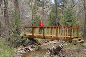 Woman standing on bridge near tent sites at Archer's Poudre River Resort in the Poudre River Valley near Fort Collins, Colorado