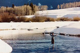 Winter fisherman wading in water with Sleepy Cat Mountain Lodging in Meeker Colorado
