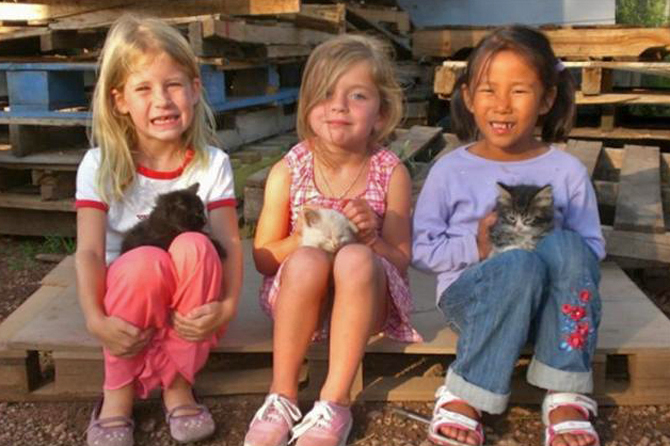 Welcome to Historic Triple B Ranch. Three kids sitting on a pallet near Triple B Ranch.