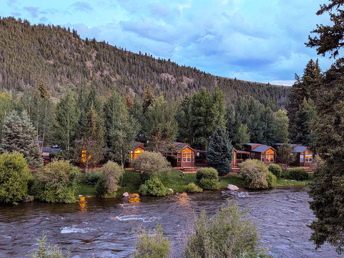 View of log-cabins along the Gunnison River with covered entries at Three Rivers Resort and Outfitting in Gunnison Colorado.