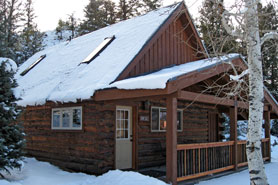 View of log-cabin in the winter with covered entry at Three Rivers Resort and Outfitting in Gunnison Colorado.