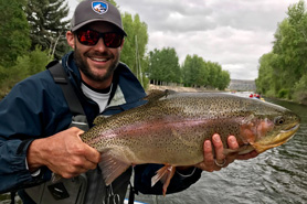 Fisherman showing off his caught rainbow trout with Three Rivers Resort and Outfitting in Gunnison, Colorado. Orvis Fly Shop. Guided Fly-Fishing Outfitting.