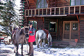 Man with horse in front of Allenspark Lodge with snow on the ground, near Estes Park Colorado