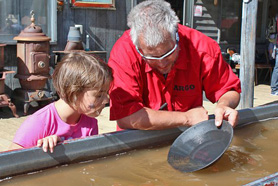 Man showing girl how to pan for gold. Discover your inner prospector as you pan for gold and gemstones at Argo Gold Mill Museum in Denver Mountain Area, Colorado.