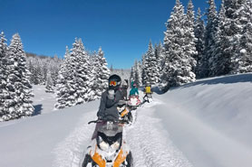Group of snowmobilers on a fresh powder trail in the Uncompahgre National Forest near Arrowhead Mountain Lodge, Restaurant and Bar in Cimarron, Colorado.