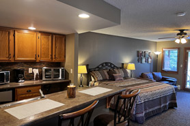 Inside view of the spa suite with in-room spa tub, gas fireplace, flat screen tv, door to patio, and built in desk at Aspen Winds on Fall River Vacation Suites in Estes Park, Colorado.