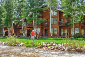 Man fly fishing in Fall River next to vacation suites at Aspen Winds on Fall River Vacation Suites in Estes Park, Colorado