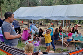 Birthday party picnic celebration with families relaxing under tent canopy and kids in hammock at Bear Mountain Stables in Conifer, Colorado.