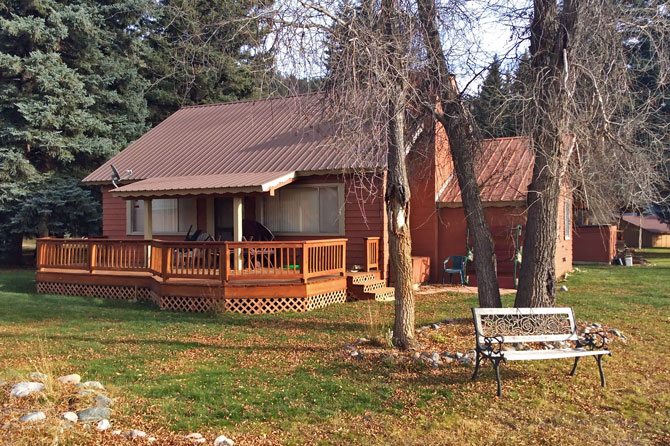 View of cabin with front porch deck and park bench during the fall at Bear Paw Lodge, Cabins, and Vacation Homes in Durango, Colorado.