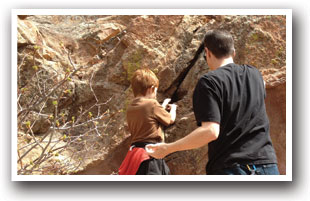 Man and boy rock climb on the Mount Sanitas Trail near Boulder, Colorado