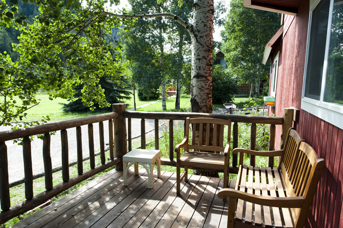 Shaded comfortable front deck with bench, chair and table at Chair Mountain Ranch Cabins in the Crystal River Valley of Marble, Colorado