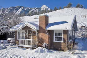 Snowy cottage with Flatirons in background at Chautauqua in Boulder, Colorado