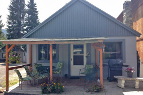 Outdoor covered patio with chairs, table and bbq grill at Columbine Cabins in Grand Lake, Colorado