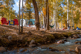 Creekside tent sites with chairs and firepite at Creekside Chalets and Cabins: Year-Round Quality Vacation Rentals in Salida, Colorado.