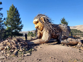 Rita the Rock Planter kneels at the edge of Victor's mining history, on Little Grouse Mountain with terraced slopes in the background, near Victor and Cripple Creek, Colorado.