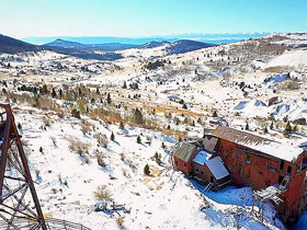 Vindicator Valley Trail glistens under a fresh dusting of snow with historic mine structures on the hillsides in Victor, Colorado.
