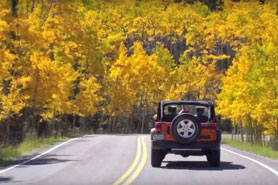 Car diving along the Highway of Legends Scenic Byway during the fall with trees changing to gold near Cuchara, Colorado.