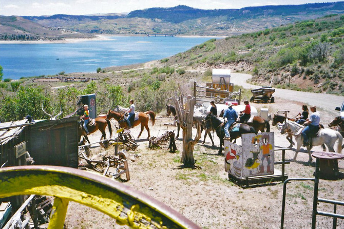 Several people horseback riding in front of Blue Mesa Lake with Ferro's Blue Mesa Ranch. Guided fishing trips. Large furnished fishing cabins on Blue Mesa Lake.
