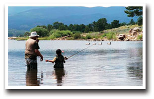 Child gets fishing tips while wading and fishing in water in Colorado
