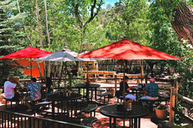 People relaxing and eating in shaded patio with umbrella covered seating tables at Garden of the Gods Trading Post, Gift Shop, and Art Gallery in Manitou Springs, Colorado
