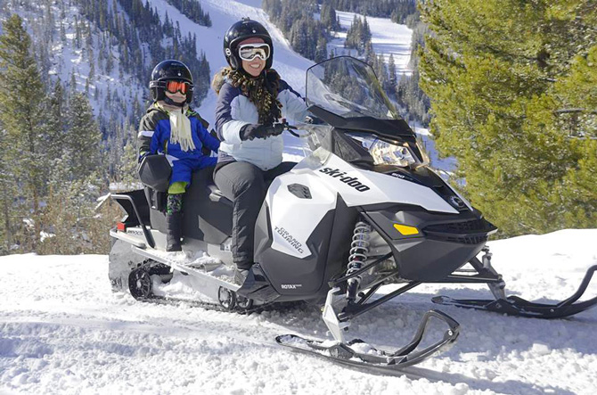 Woman and child on snowmobile in snow rented with Grand Adventures in the Winter Park area, Colorado