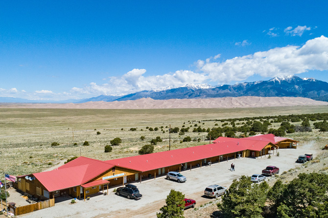 View of Great Sand Dunes Lodge with the Great Sand Dunes National Park and snow capped Sangre De Cristo Mountains in the background located in Alamosa, Colorado.