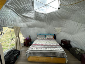 Inside view of Glamping Geodesic Dome with queen bed, portable heater, power outlets and skylight at Great Sand Dunes Lodge in Alamosa, Colorado.