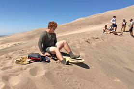 Sandboarder preparing to surf a dune on a sled at Great Sand Dunes National Park and Preserve near Great Sand Dunes Oasis Campground in Mosca, Colorado.