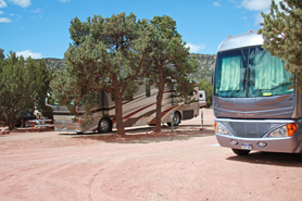 Big RVs parked in shaded sites with picnic tables at Indian Springs Ranch and Campground in the Royal Gorge area of Colorado.