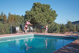 Family having water-gun battle next to outdoor swimming pool at Indian Springs Ranch and Campground in the Royal Gorge area of Colorado.