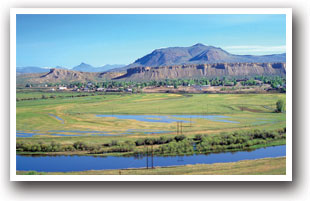 Kremmling Colorado with river and farmland in foreground with bluffs behind city