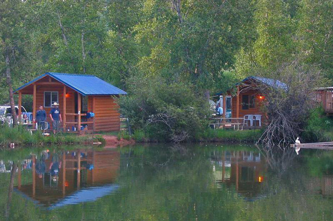 Camper cabins next to a pond surrounded by aspen tress at Lone Duck Campground in Cascade, Colorado