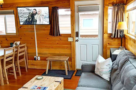 Inside view of cabin with couch, dinner table and flat screen tv at Lupin Village at Grand Lake, Colorado.