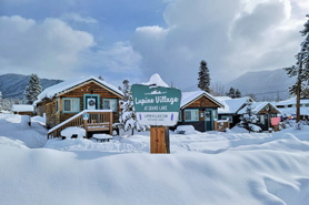 Welcome sign and row of cabins blanketed in snow at Lupin Village at Grand Lake, Colorado.
