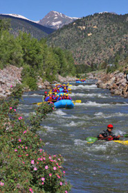 Whitewater rafting tour and kayaker going down the Arkansas River with Clear Creek Rafting Company in Colorado
