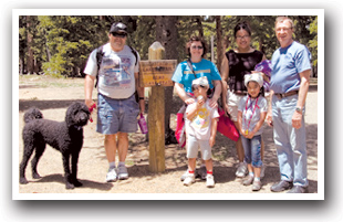 Family in front of hiking trail sign on Mount Evans Scenic Byway, Colorado.