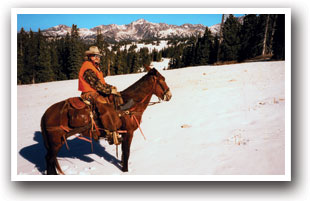 Cowboy on horse in the snow over looks Mancos Valley in Colorado