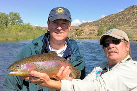 Fishing guide and fisherman with caught rainbow trout in Navajo Dam, New Mexico