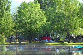 Tents set up in camping sites with bbq grills, picnic tables and fire pites at Pagosa Riverside Campground and Camper Cabins in Pagosa Springs, Colorado.