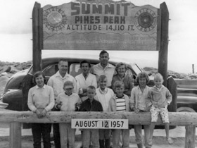 Antique era-1957 black and white photo of family under the Pikes Peak Toll Road Summit sign near Colorado Springs, Colorado.