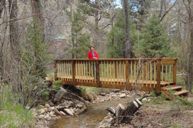 Woman standing on bridge near tent sites at Poudre River Resort in the Poudre River Valley near Fort Collins, Colorado.