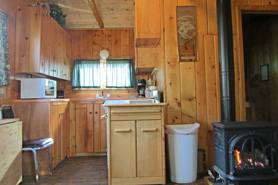 View of kitchen and gas fireplace inside of cabin 3 at Poudre River Resort in the Poudre River Canyon near Fort Collins, Colorado.