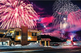 exterior of Rabbit Ears Motel at night with fireworks in the sky above hotel and Steamboat Springs, Colorado