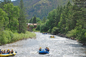 Rafters going down the Cache La Poudre River with trees and mountains in Colorado. Photo courtesy of Boy Scout Troop 77 - Boulder, CO