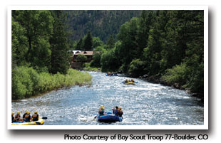 Rafters going down the Cache La Poudre with trees and mountains, Photo courtesy of Boy Scout Troop 77 - Boulder, CO