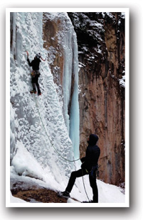 A ice climbing spotter watches as ice climber climbs a frozen waterfall near Rifle, Colorado